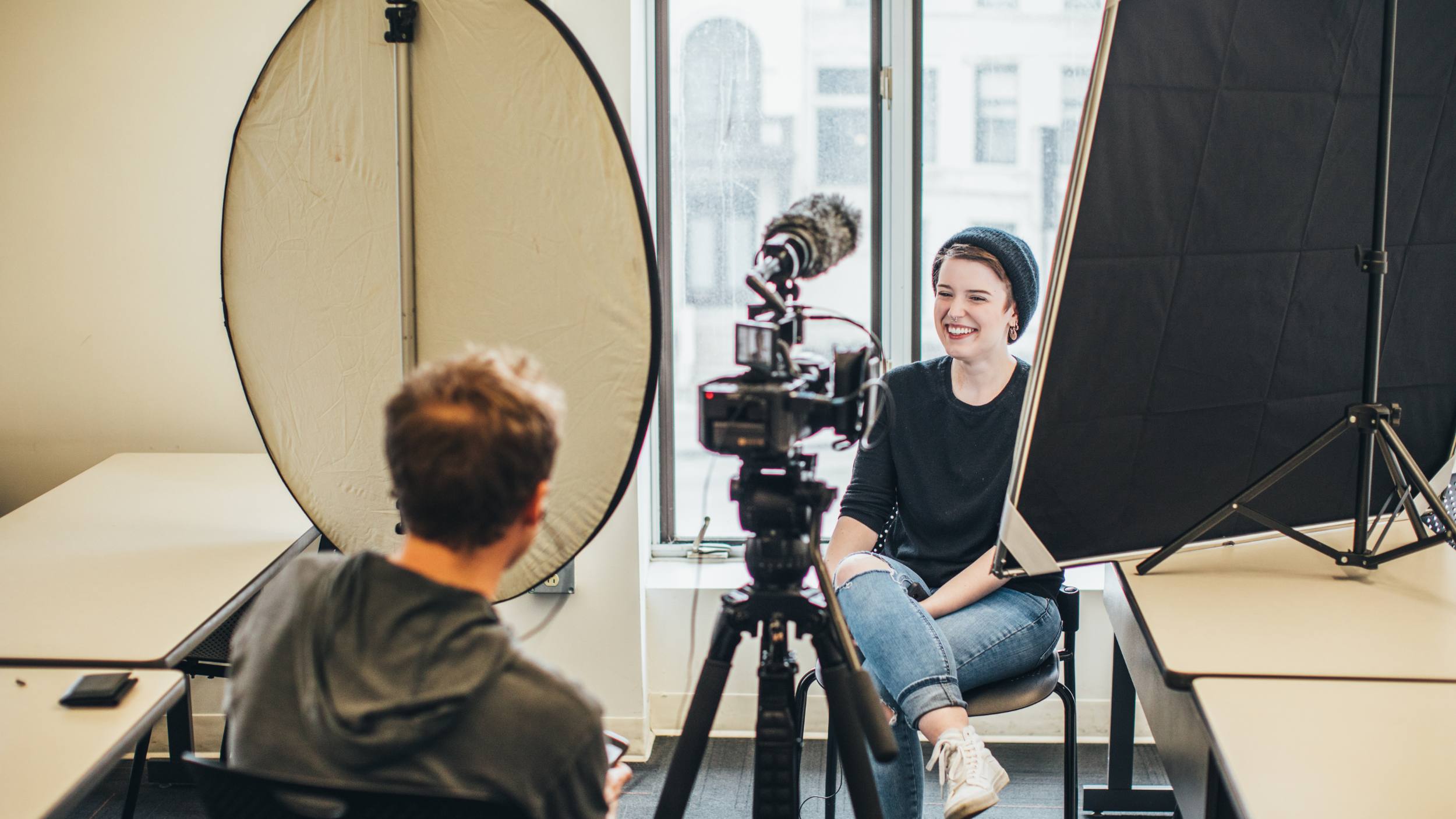 Students filming an interview in a classroom, smiling