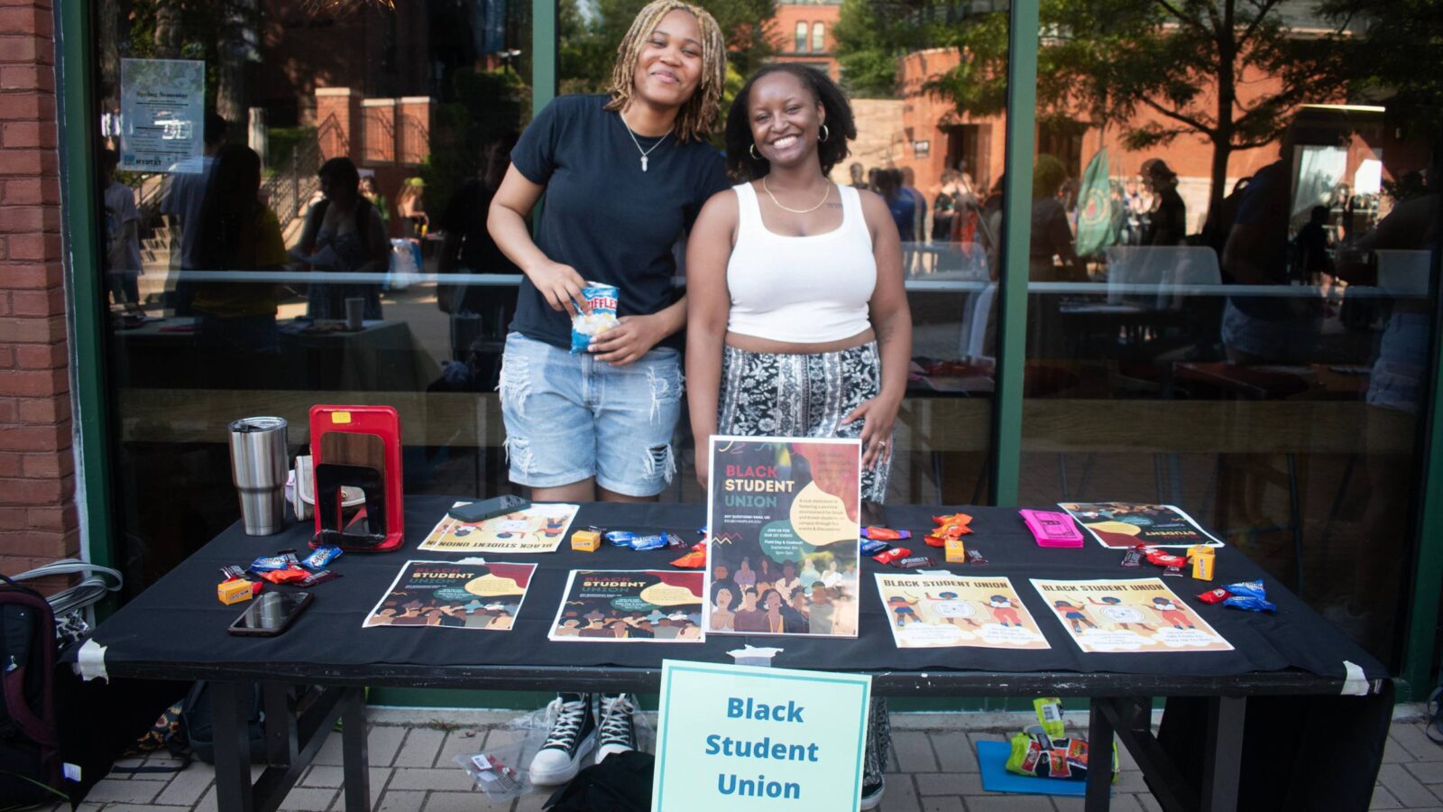 Students tabling at the activity fair, posing for a photo behind the Black Student Union signs