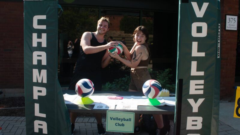 Students holding a volleyball in the courtyard tabling at the activity fair for their club