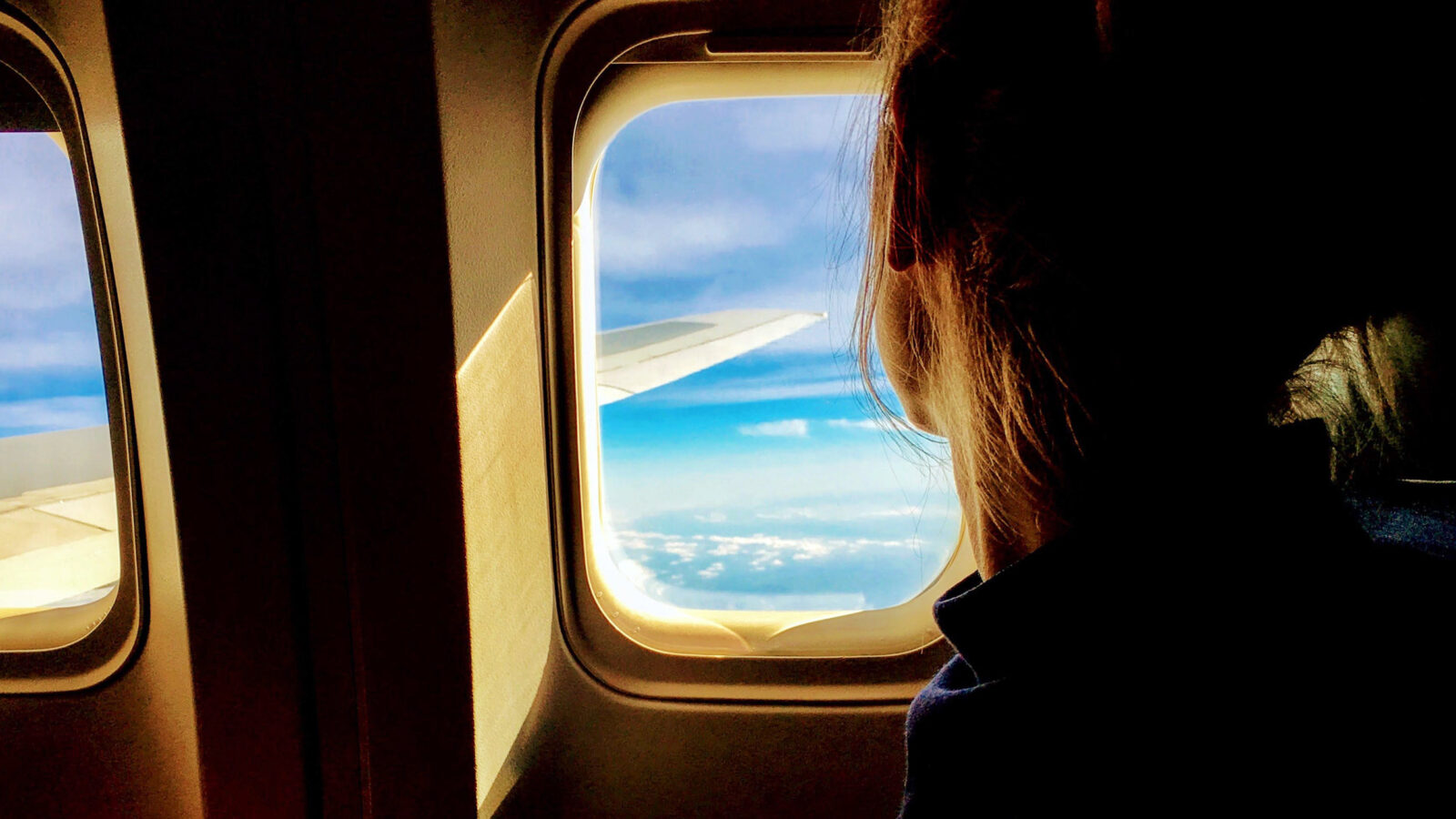 young woman looking out the window of an airplane