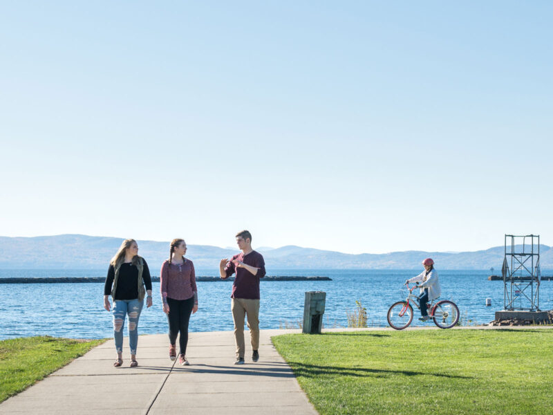 Three Champlain students stroll the Waterfront Park in Burlington, Vermont, on a clear day.