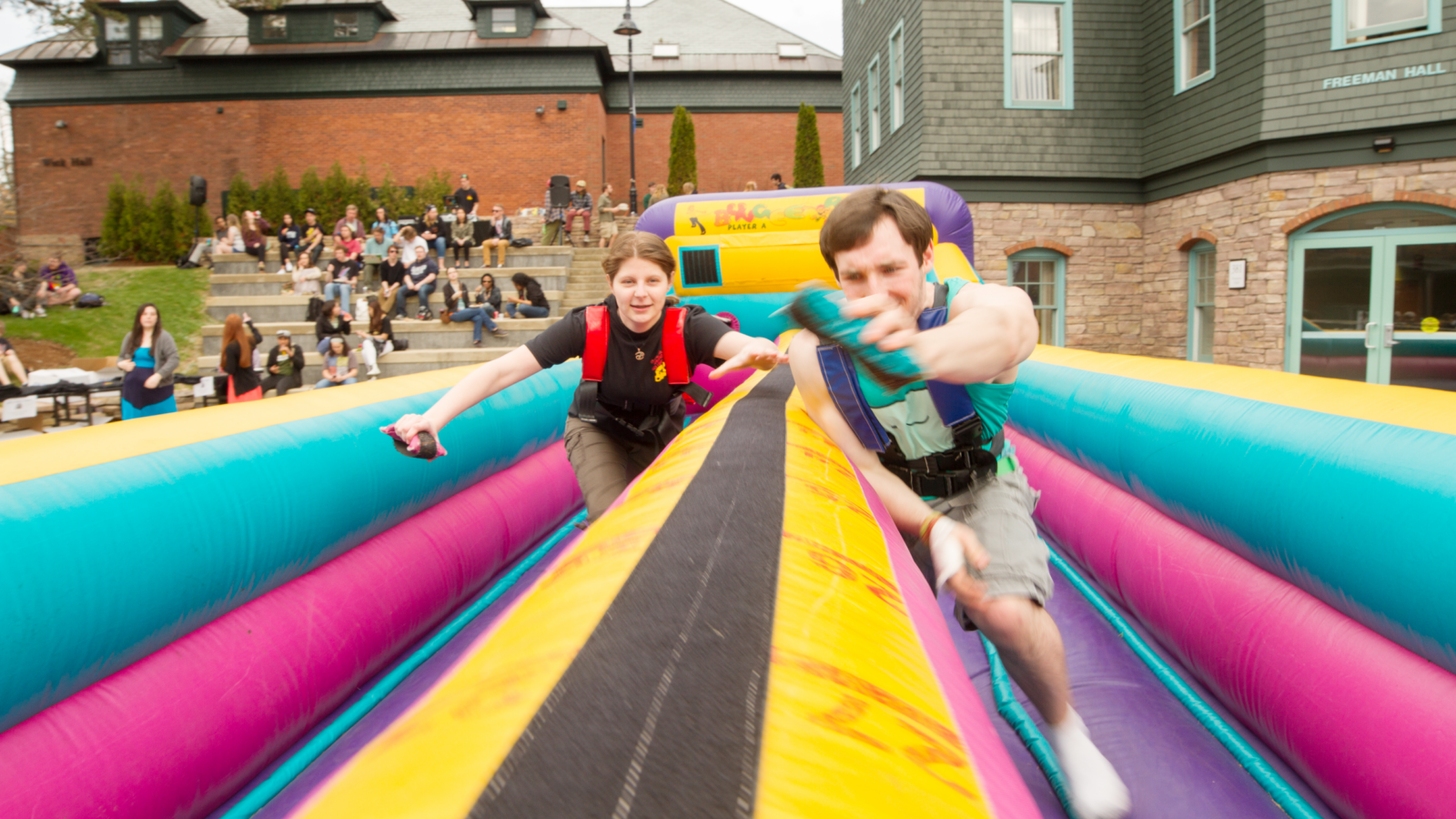 Two students race on an inflatable obstacle course.