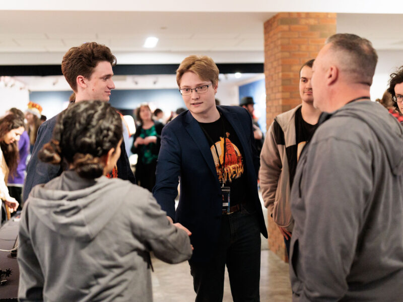Student shakes hands with a potential employer at the Senior Show after party.