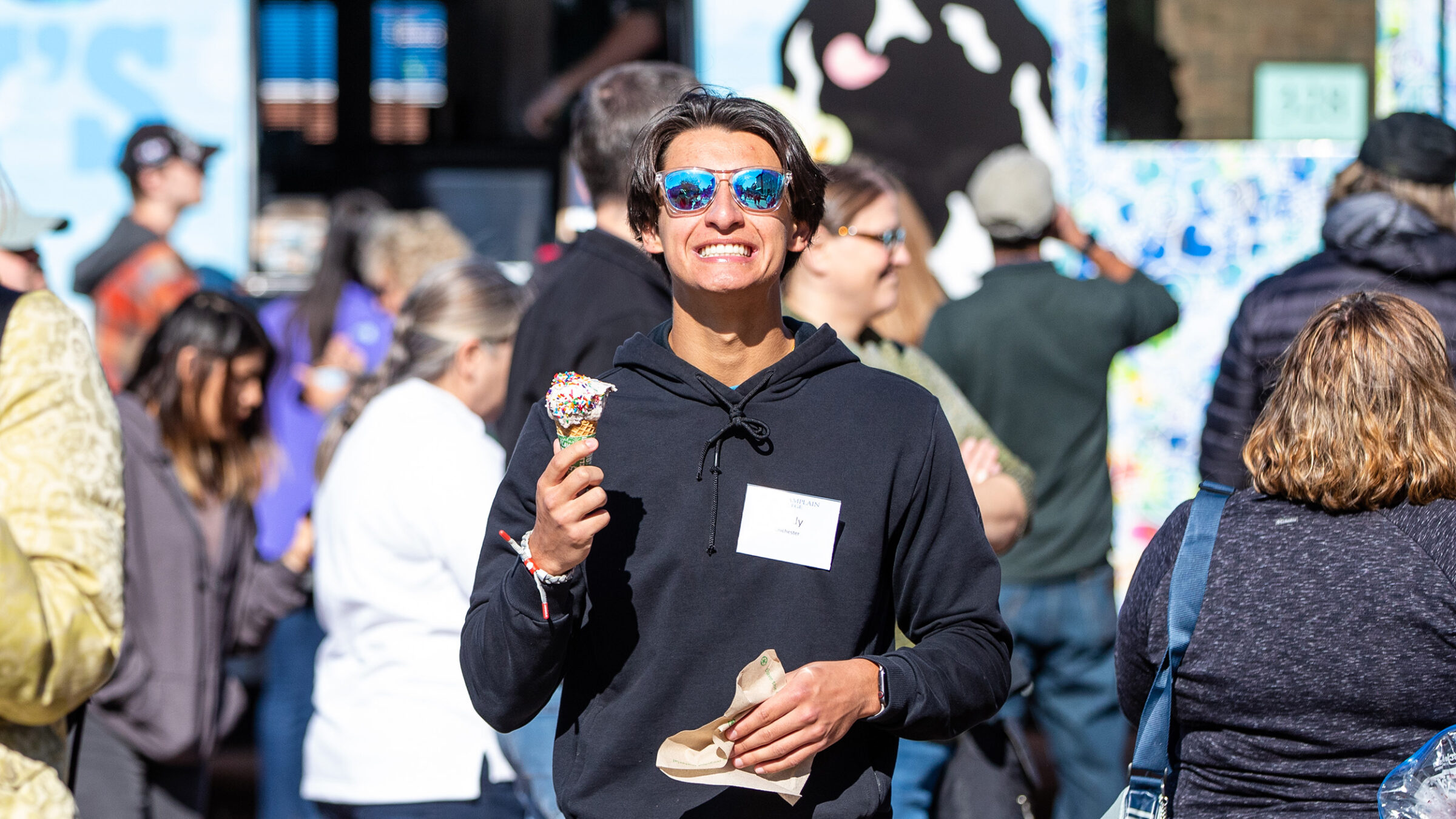 Student smiles wide while eating an ice cream cone in front of a Ben & Jerry's mobile scoop truck.