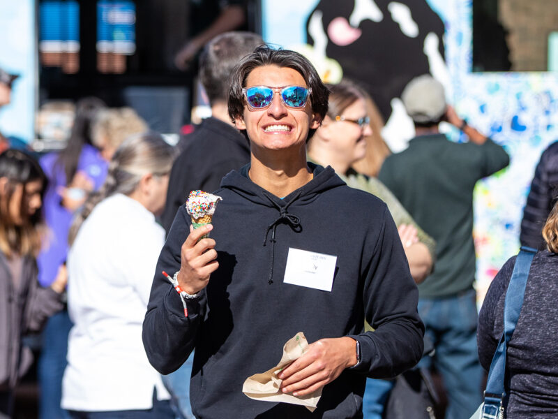 Student smiles wide while eating an ice cream cone in front of a Ben & Jerry's mobile scoop truck.