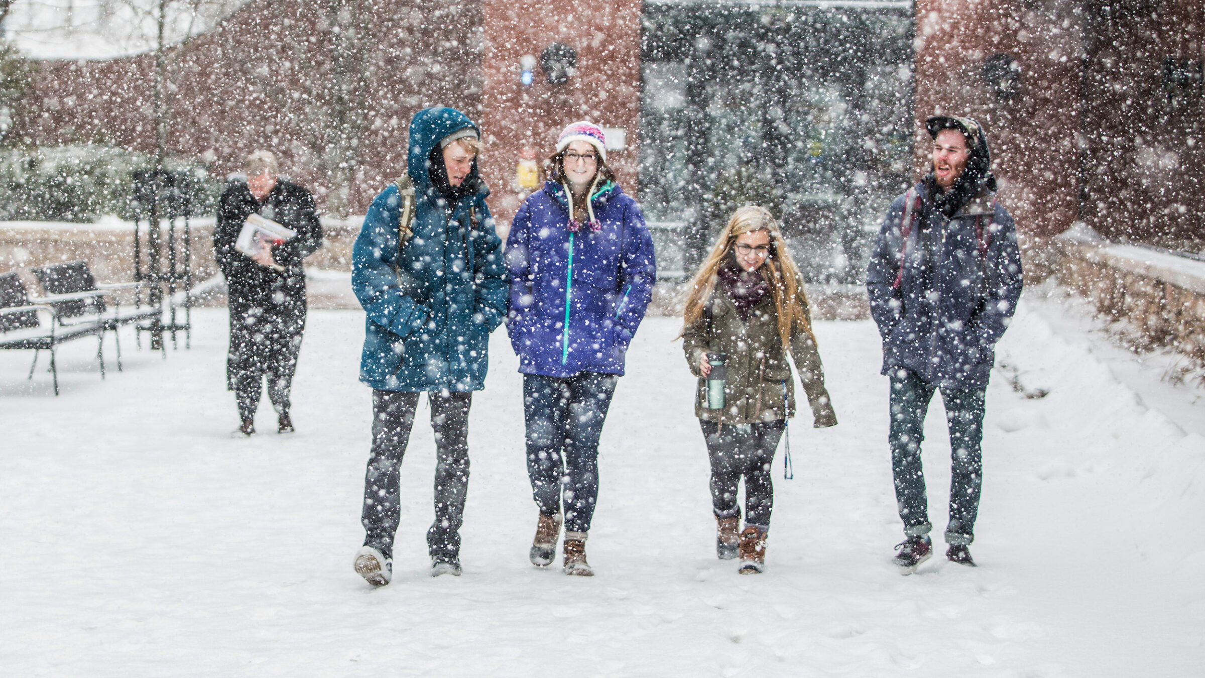 a group of students walk on campus during a heavy snow fall