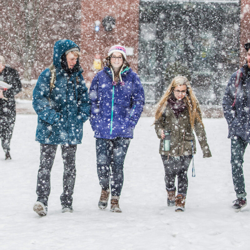 a group of students walk on campus during a heavy snow fall
