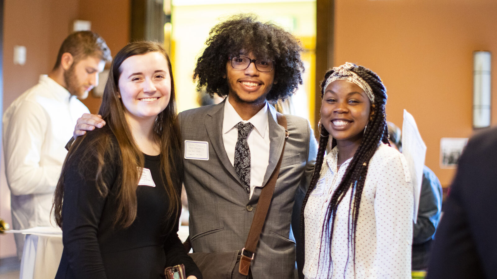 three students at networking event pose for camera