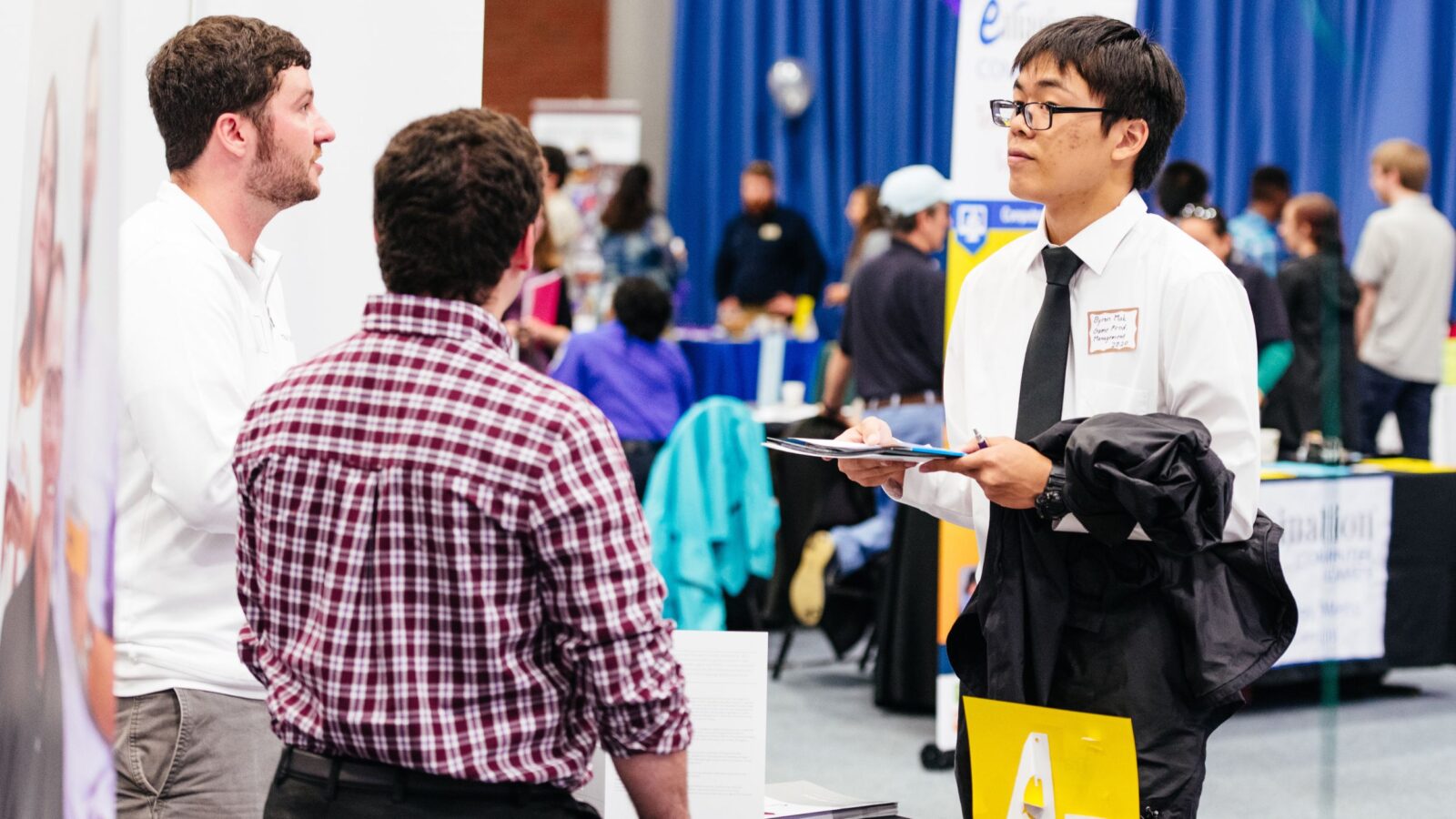 students conversing with company reps at a career fair