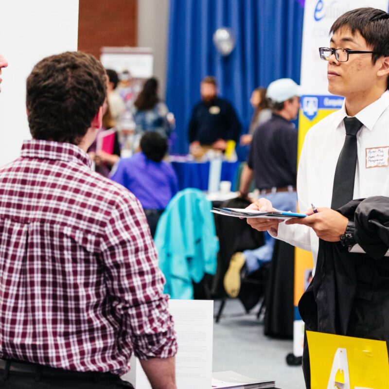students conversing with company reps at a career fair