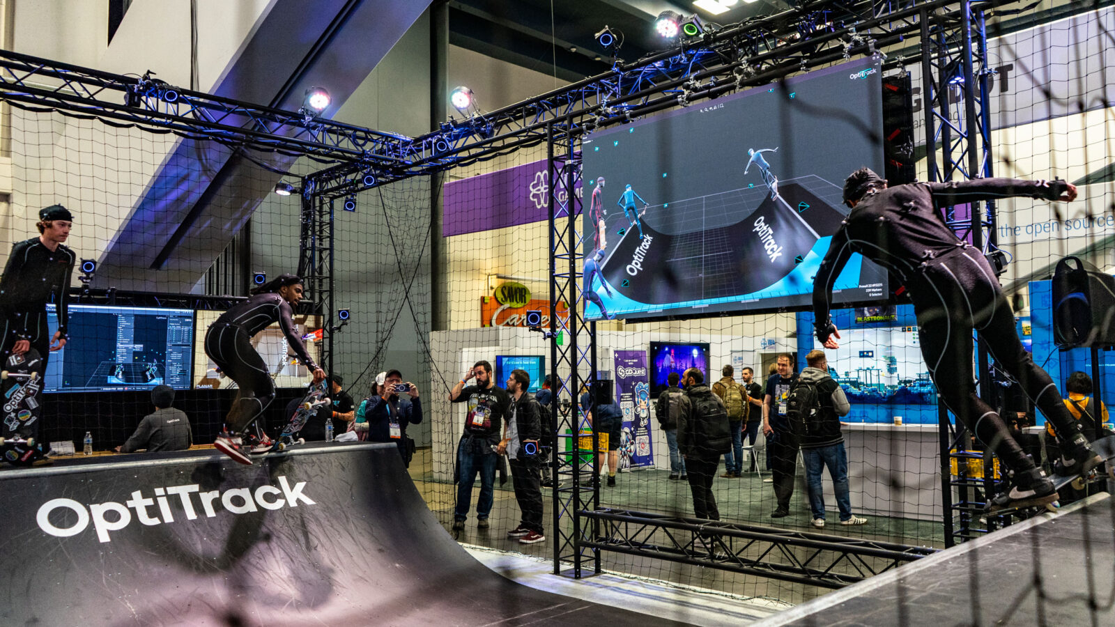Two people skateboard on a halfpipe wearing motion sensors at the Game Developers Conference.
