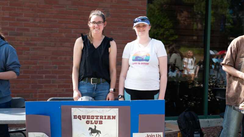 Two students standing at the Equestrian Club table outside of IDX at the Activities Fair on campus