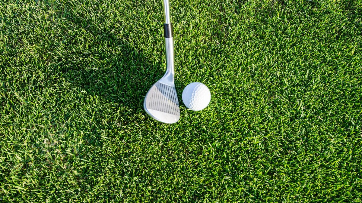 a golf ball and club on green grass