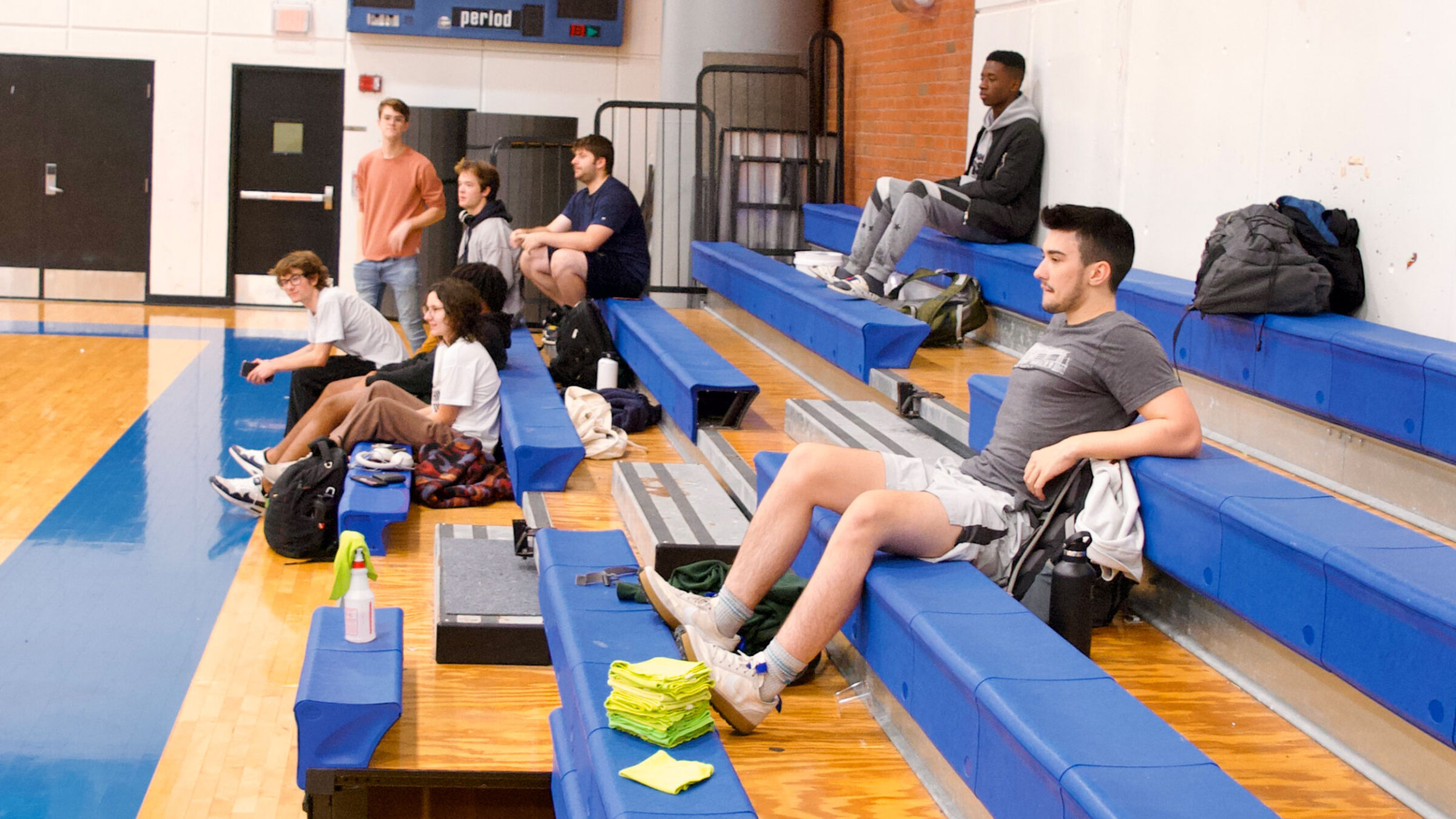 A handful of students rest on the bleachers inside the Argosy gymnasium at Champlain College.