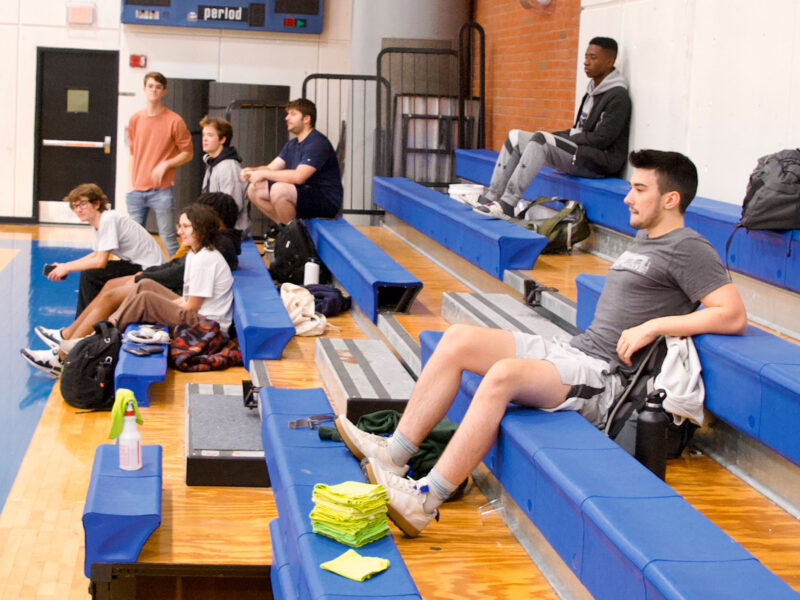 A handful of students rest on the bleachers inside the Argosy gymnasium at Champlain College.