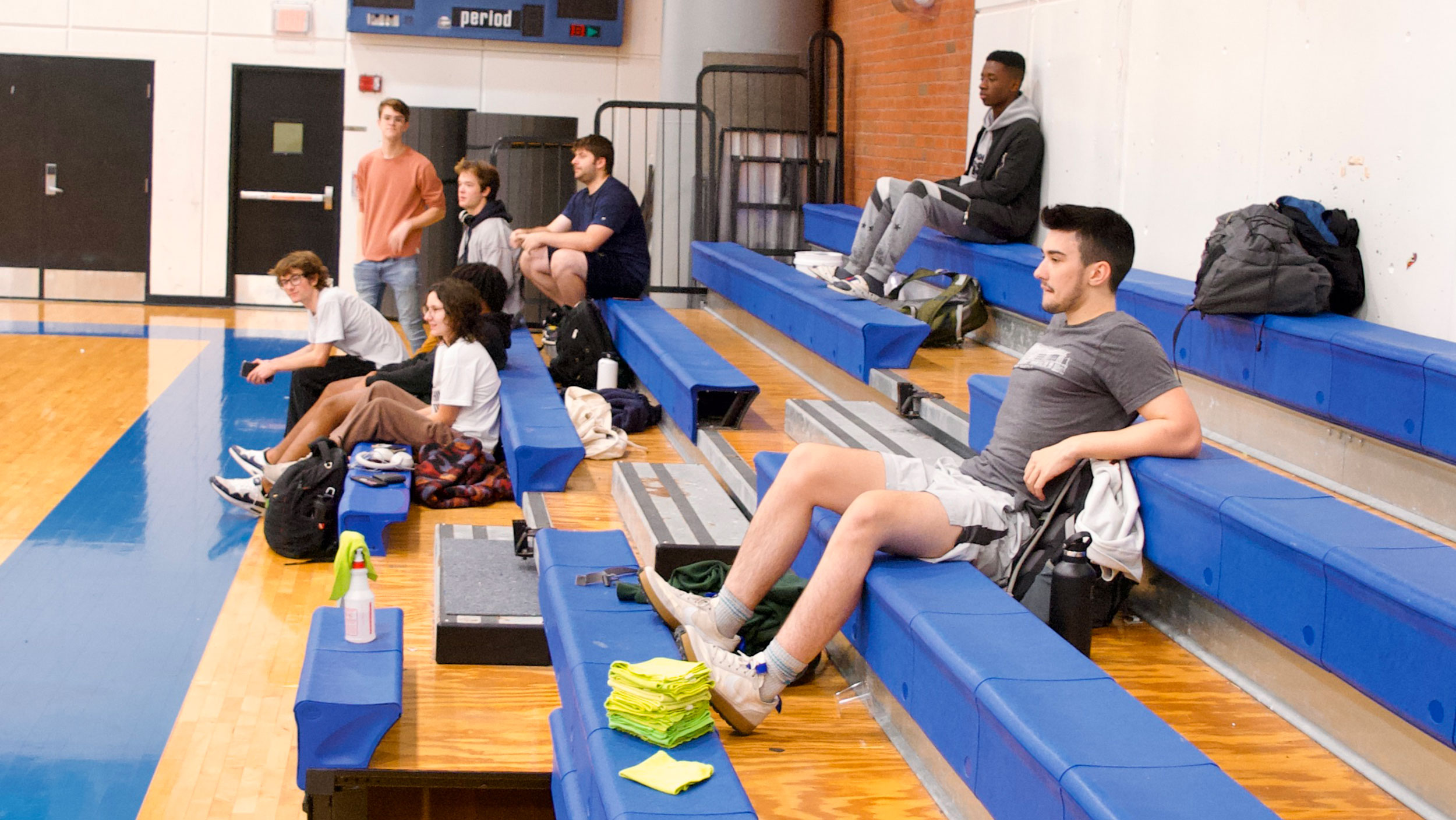 A handful of students rest on the bleachers inside the Argosy gymnasium at Champlain College.