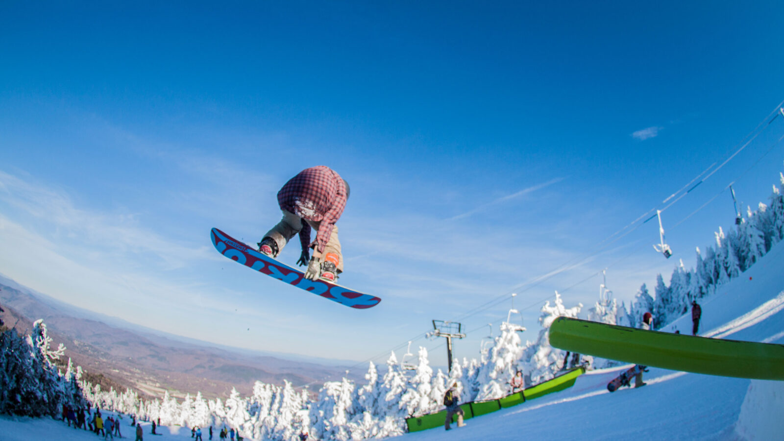 A snowboarder is mid-air after hitting a jump.