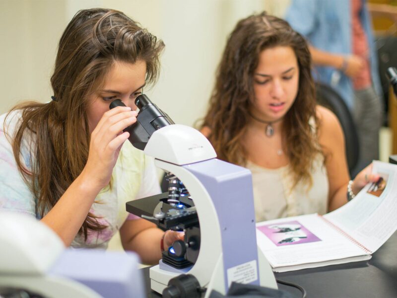 criminal justice student analyzing samples through a microscope