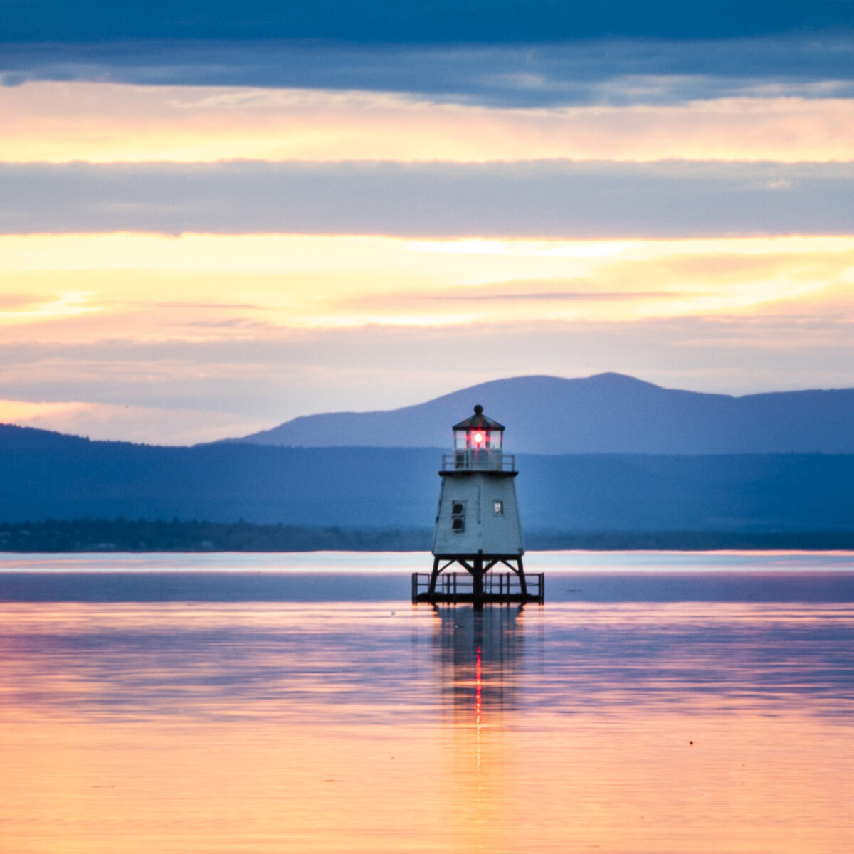 a small lighthouse on Lake Champlain during sunset