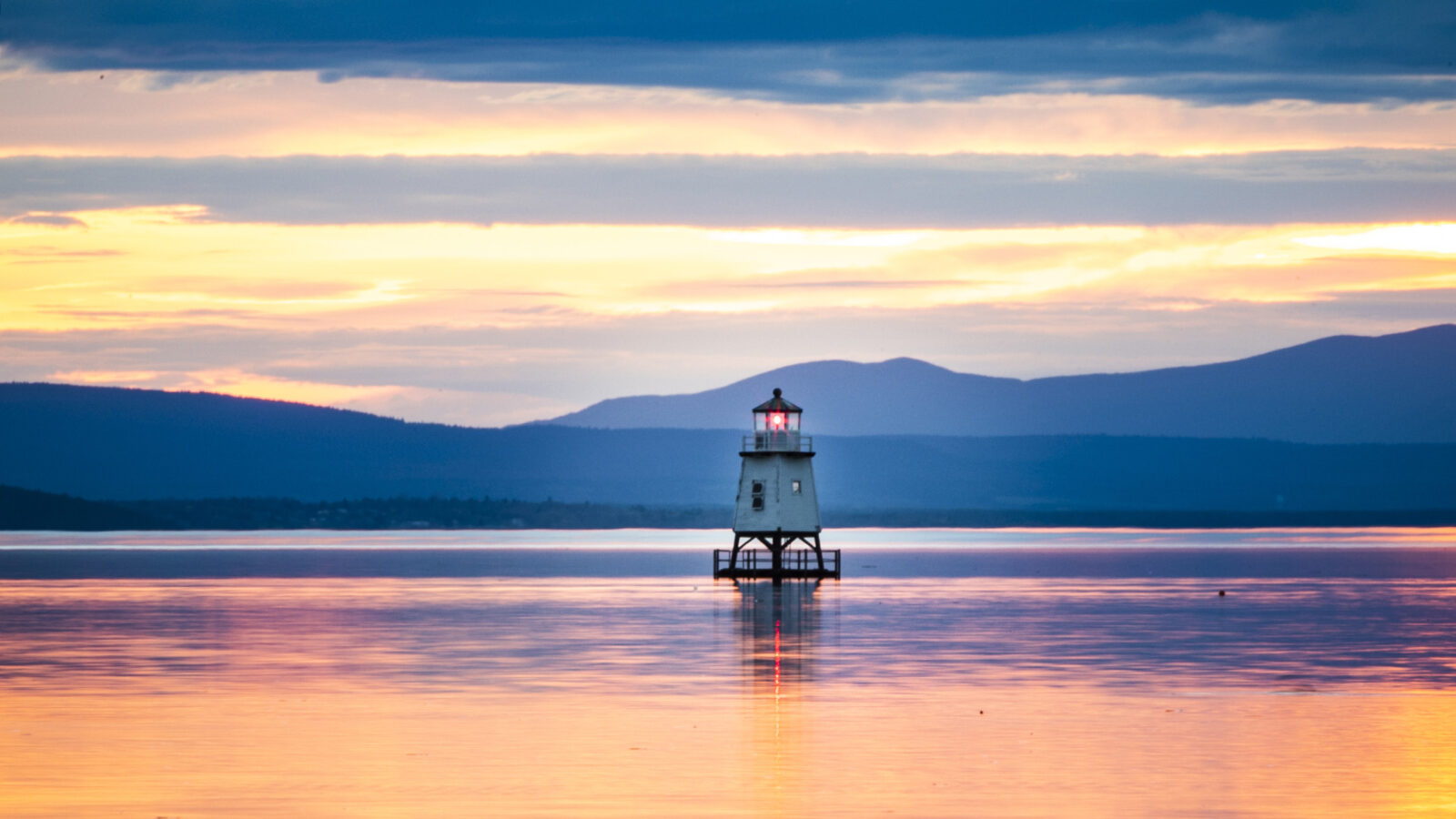 a small lighthouse on Lake Champlain during sunset