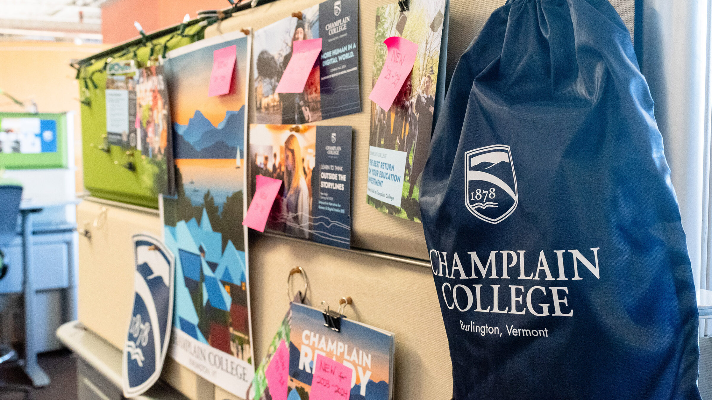 various marketing materials such as postcards and a string backpack pinned to a wall as samples