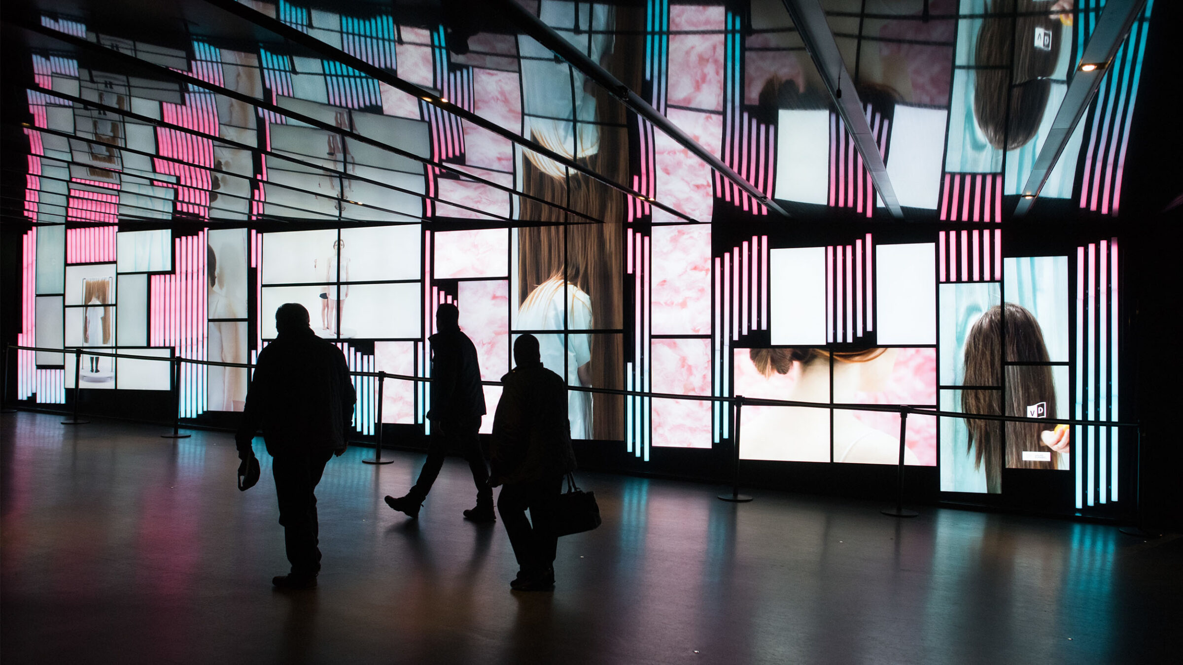 three individuals walking past a digital art display in montreal, canada