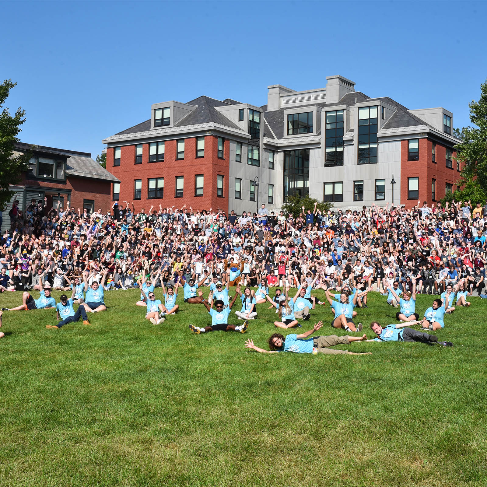 hundreds of new students gather on a campus green with matching blue t-shirts for orientation