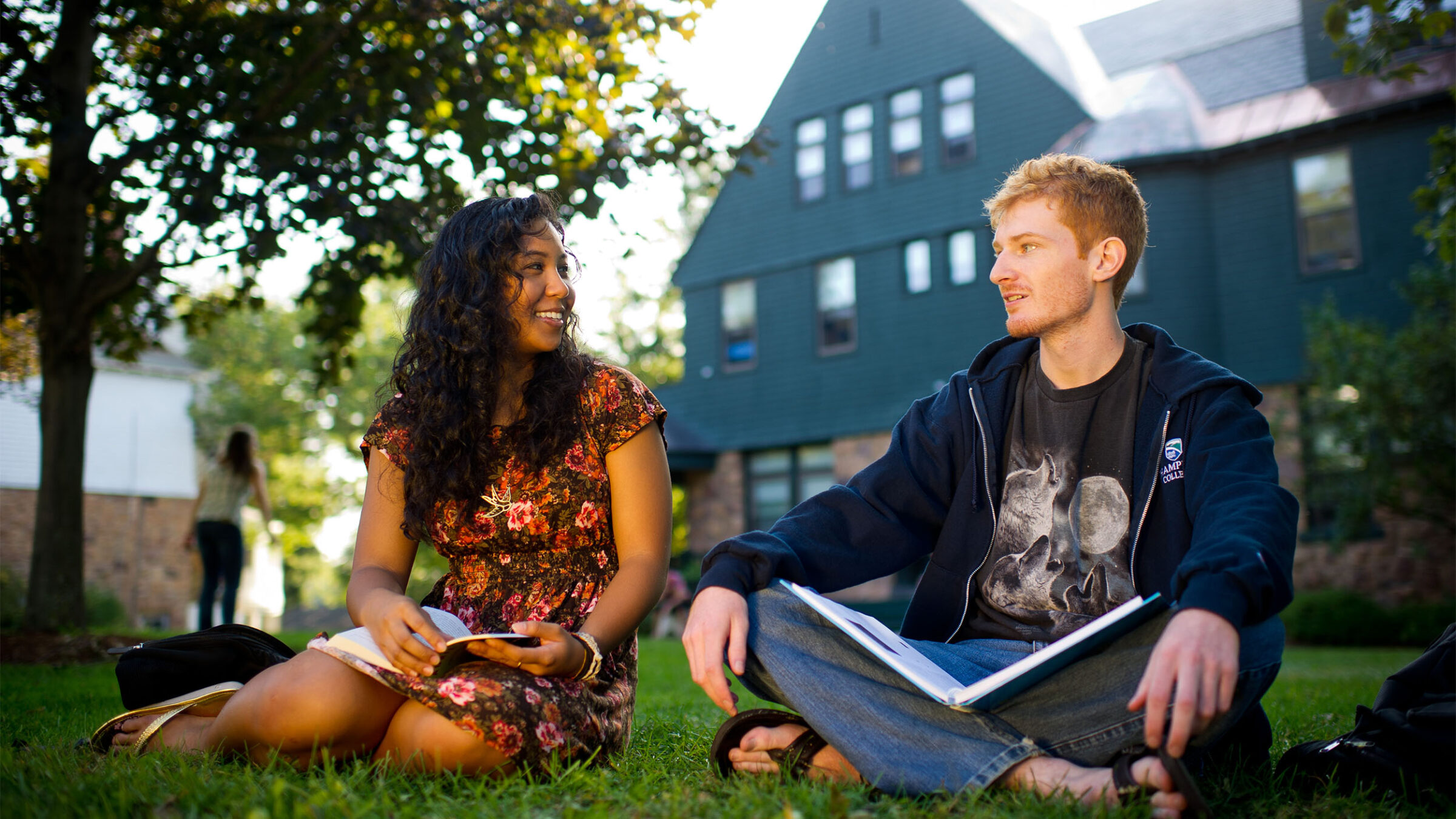 two students studying together in the grass on campus