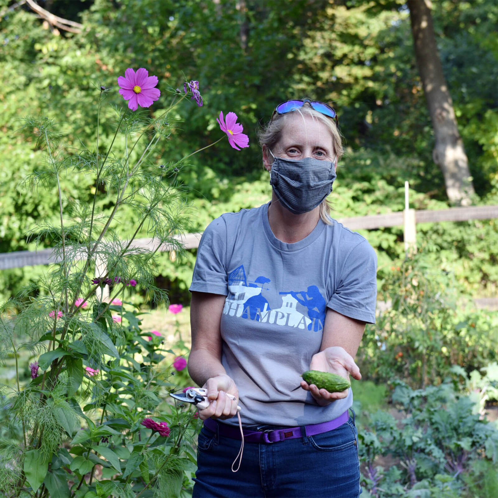 Center for Service & Sustainability Director, Christina Erickson holding a cucumber freshly harvested by a garden