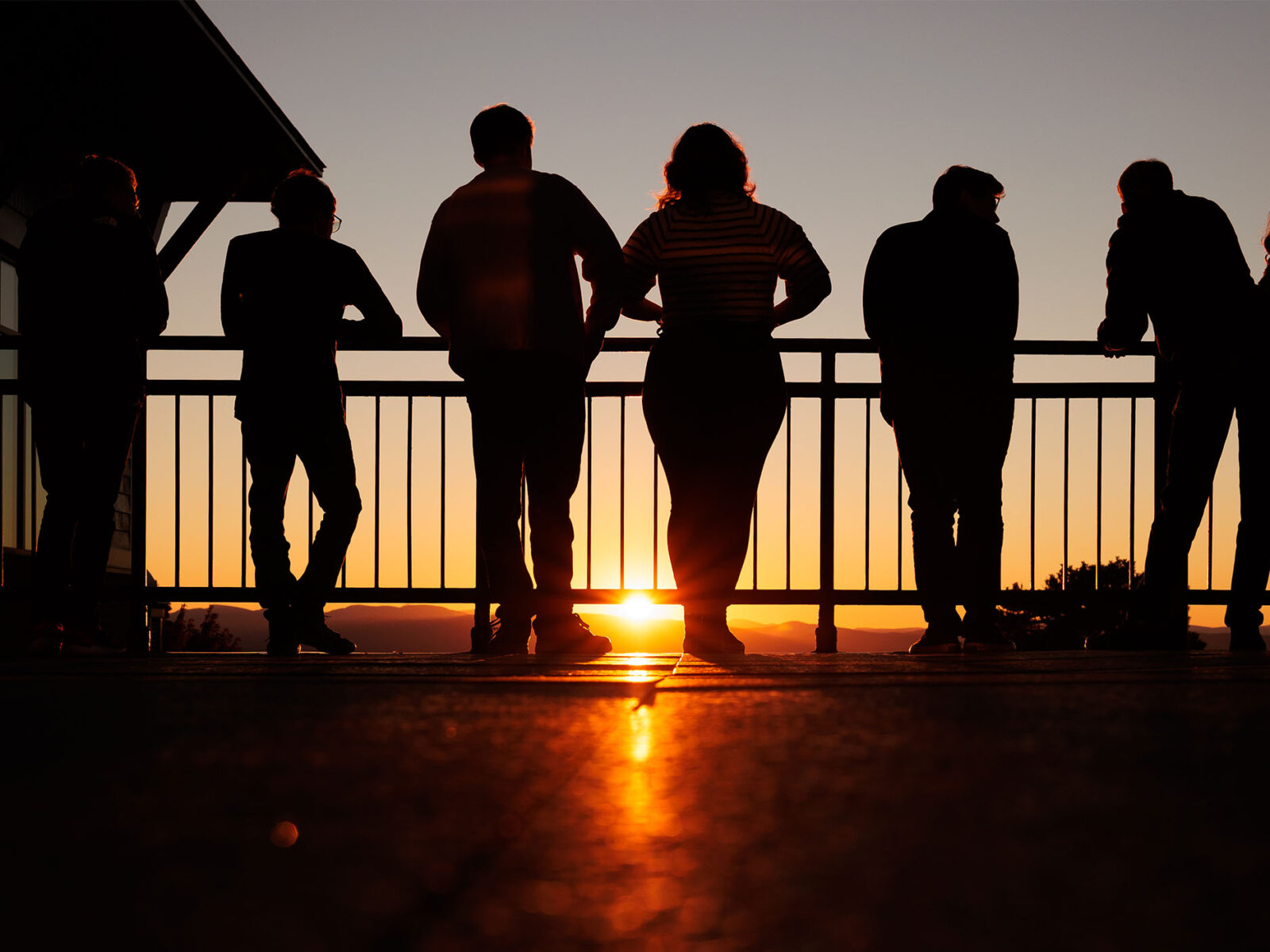 a group of students watching the sunset from atop a champlain college balcony