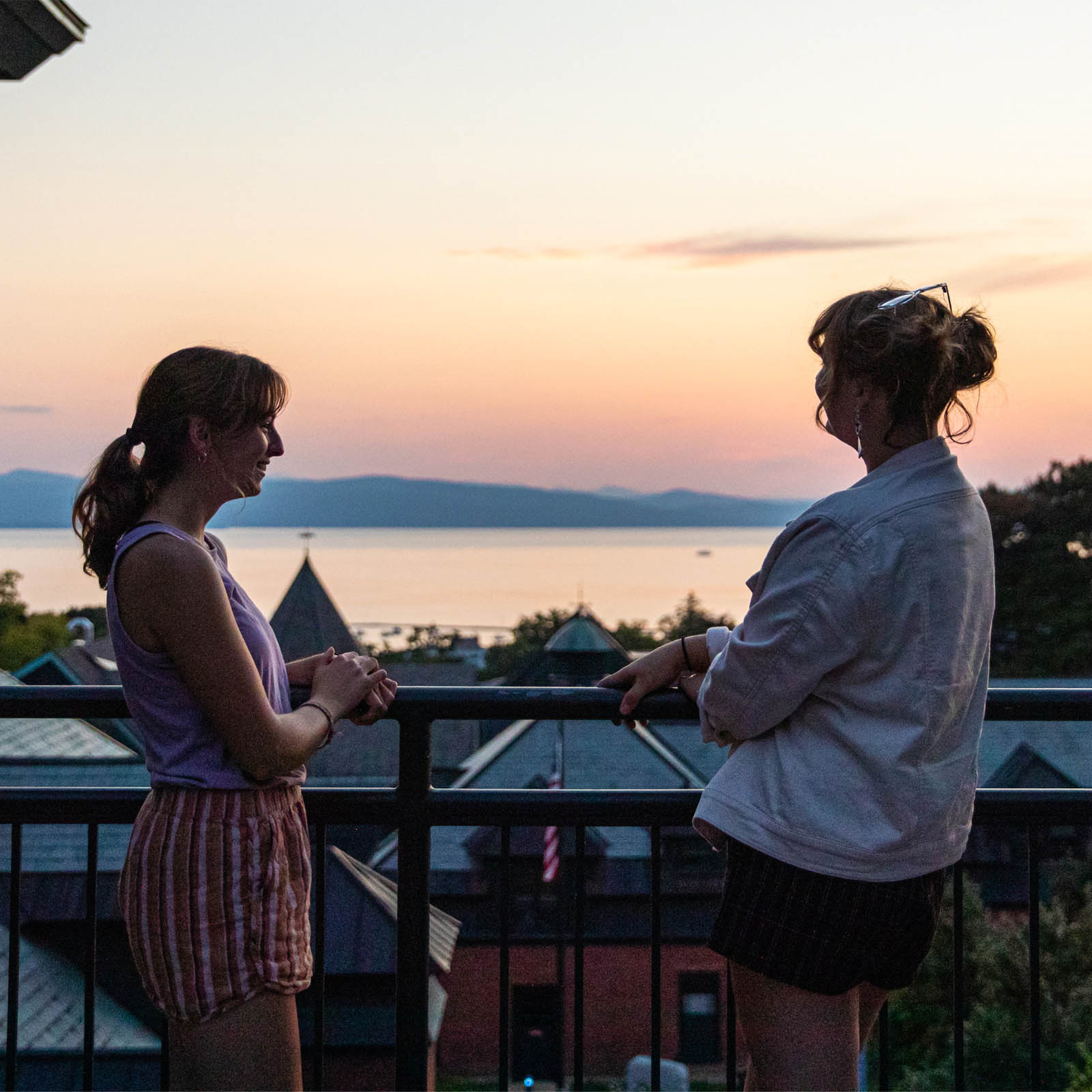 two students chatting on a patio during sunset