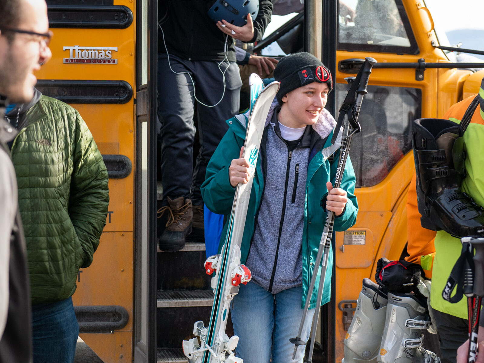 student getting off the bus at sugarbush ski resort holding skis and poles