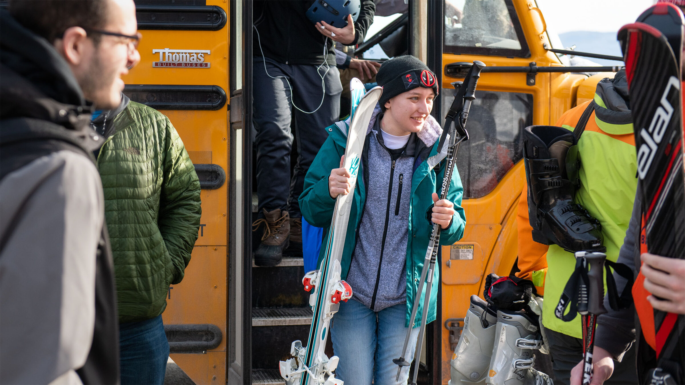 student getting off the bus at sugarbush ski resort holding skis and poles