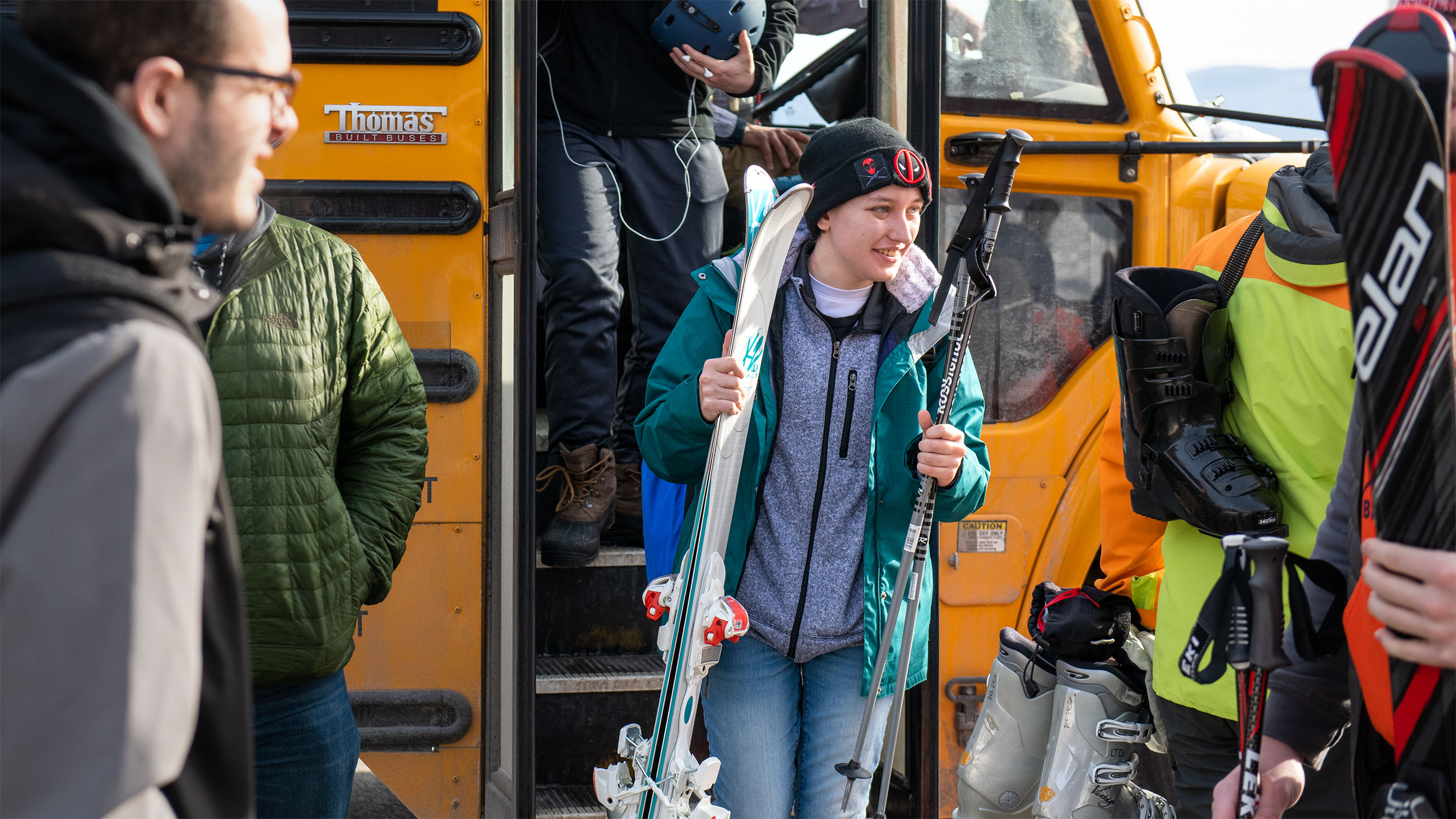student getting off the bus at sugarbush ski resort holding skis and poles