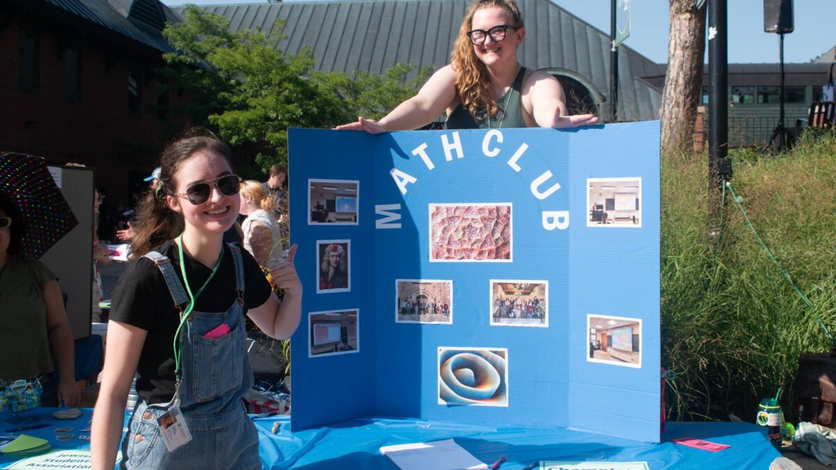 Students excited standing next to the Champlain Math Club poster at the activity fair