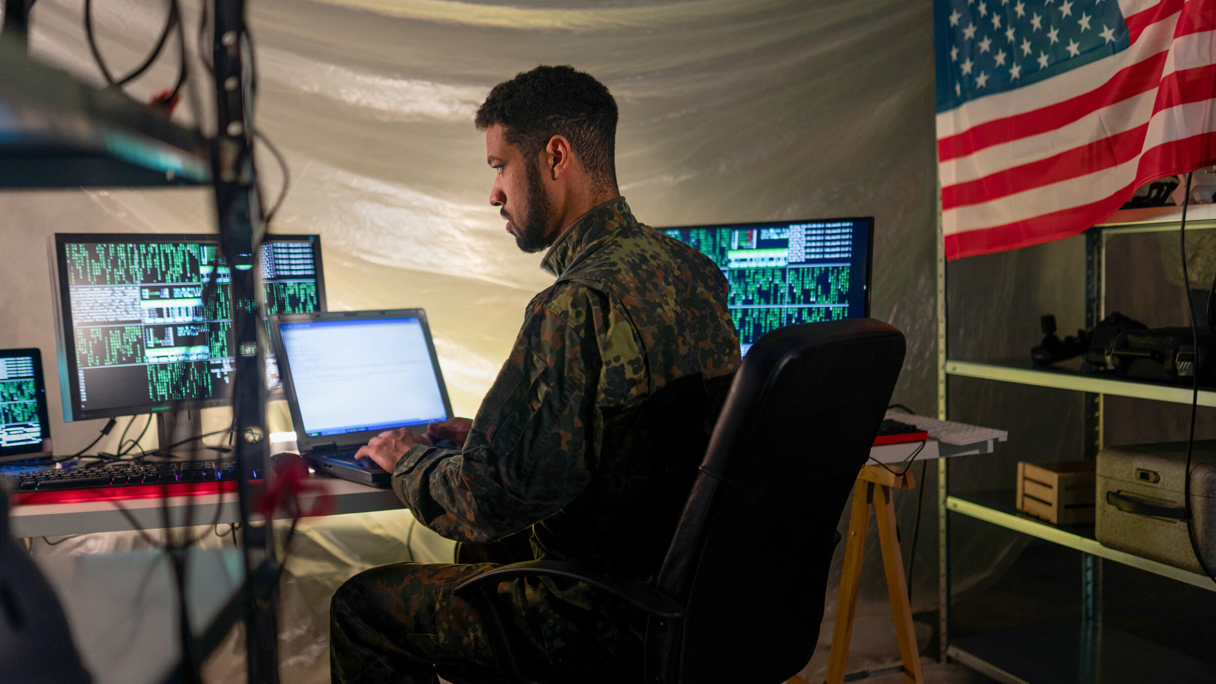 solider works on a laptop in a tent