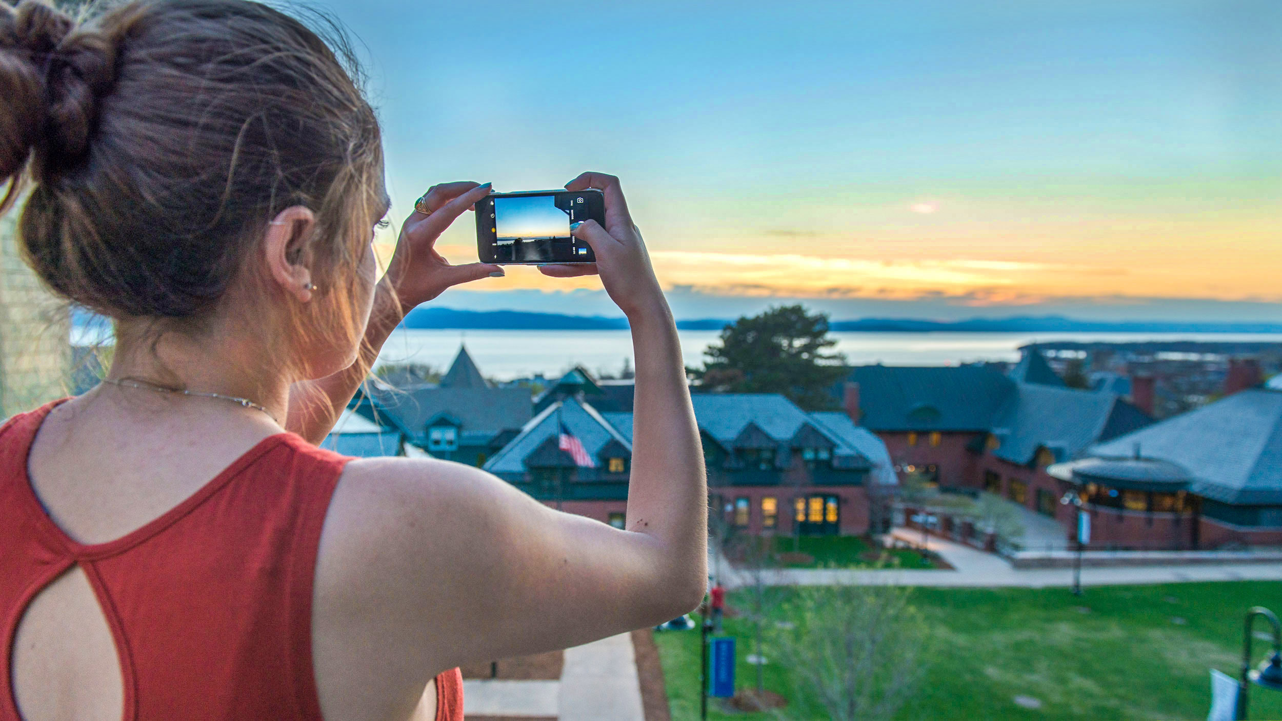 student taking a photo of the lake from the library balcony