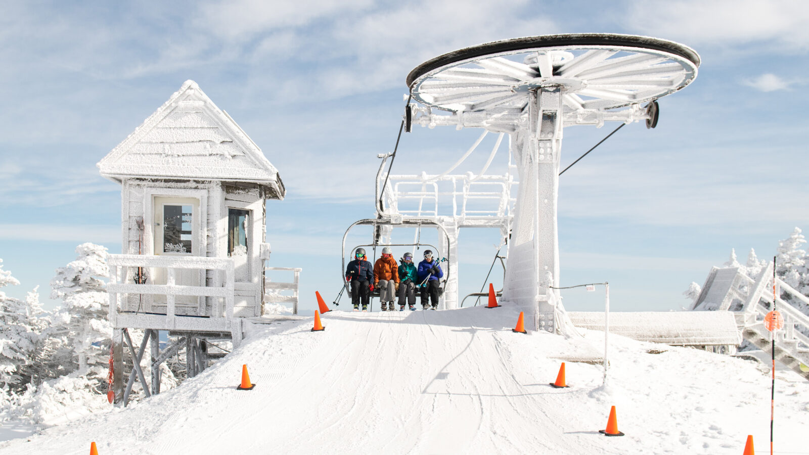 four people on the chair of a ski lift