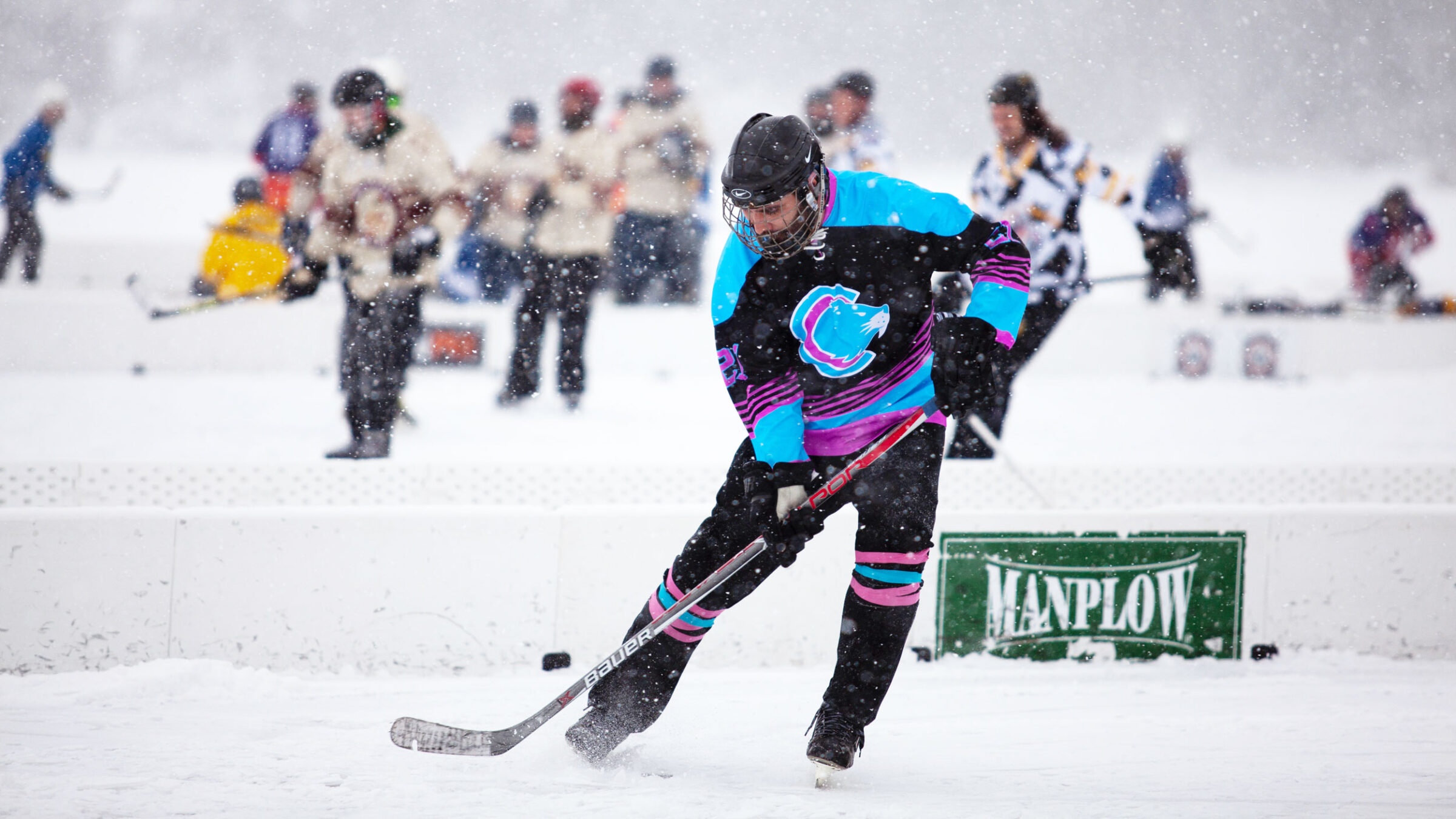 A hockey player takes a shot with the puck during a game played on a frozen lake.