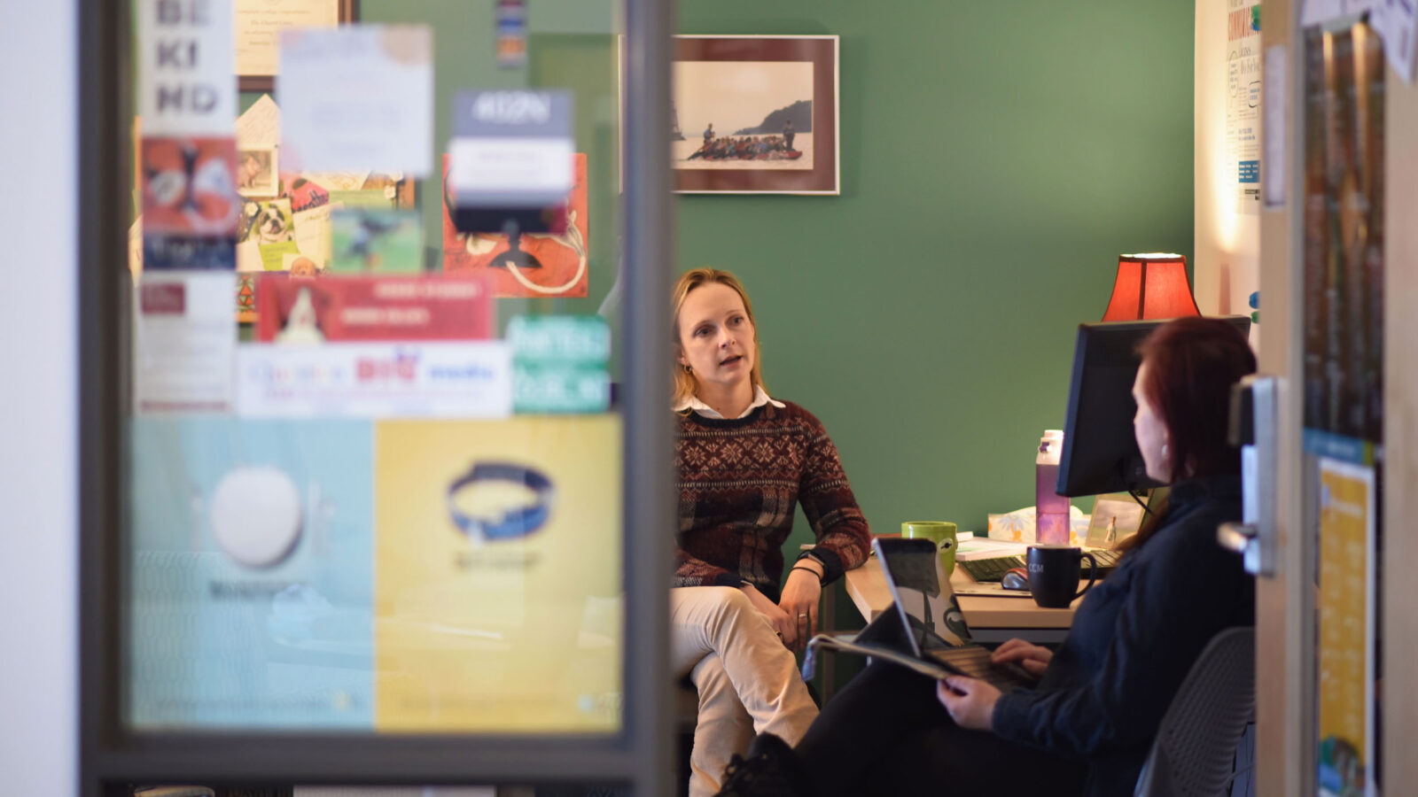 A faculty member advises a student in their office.