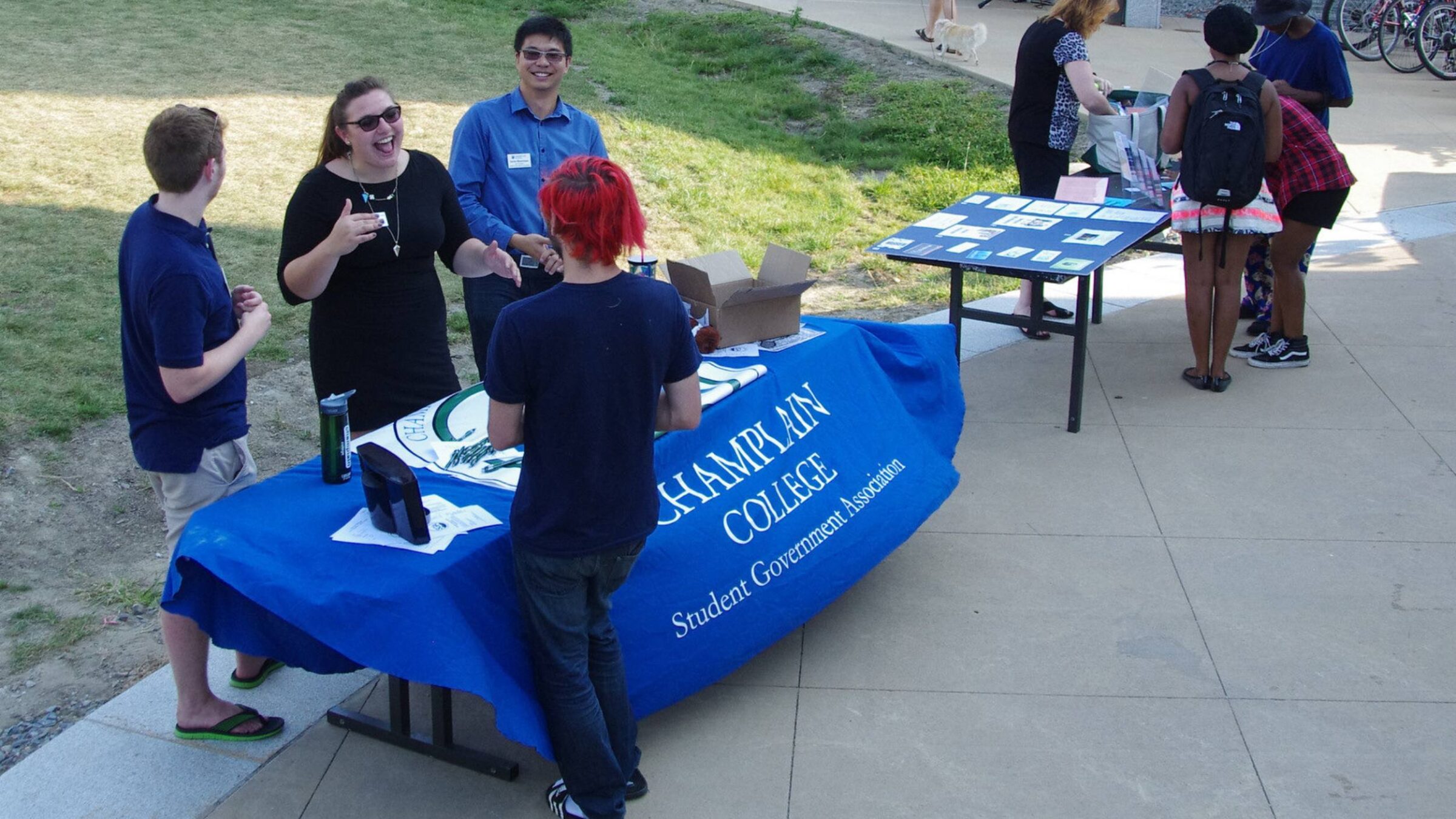 Students outside finny quad tabling for the student government association with interested students chatting