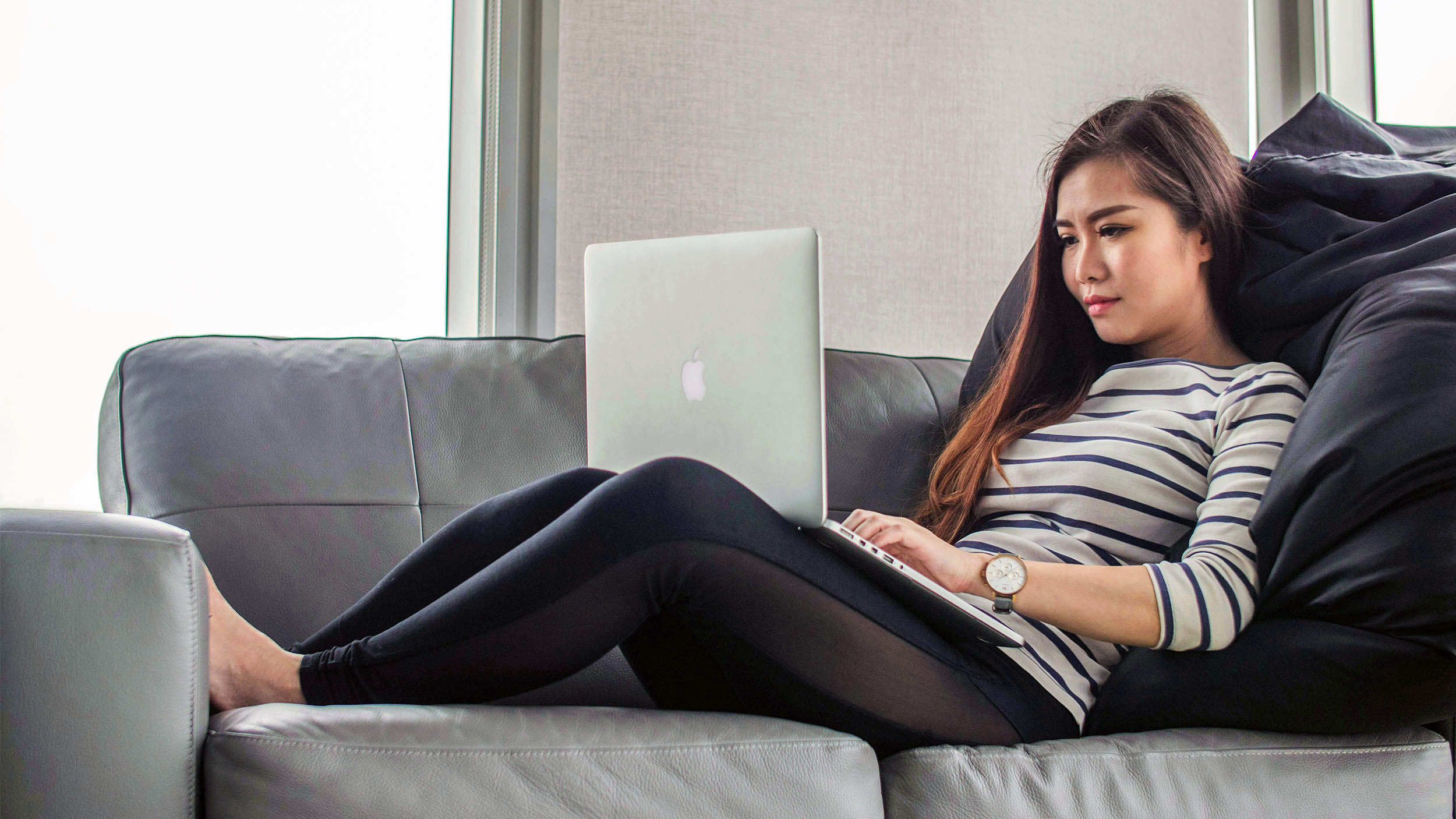 student sits on the couch looking at an open laptop on their lap