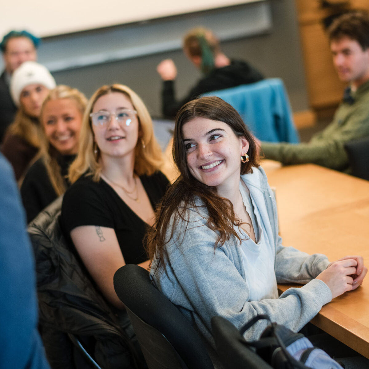 students at a table watch the professor write on a white board