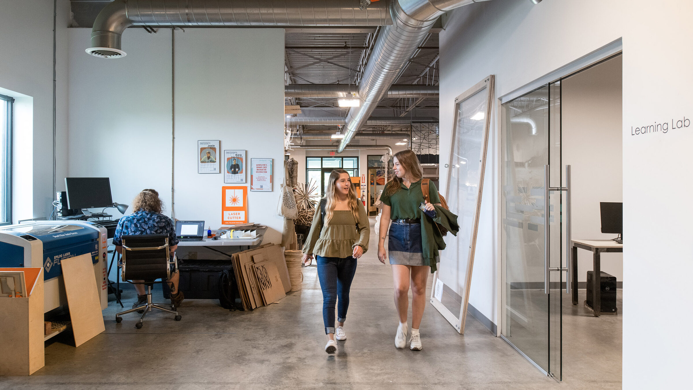 students walk through Generator building, creative materials in background