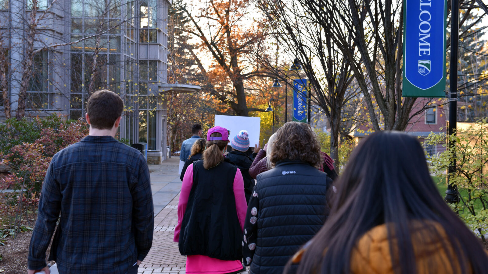 backs of peoples heads as they walk throughout campus at sunset