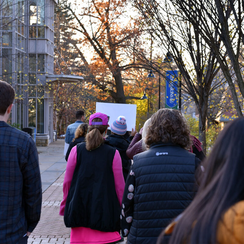 backs of peoples heads as they walk throughout campus at sunset