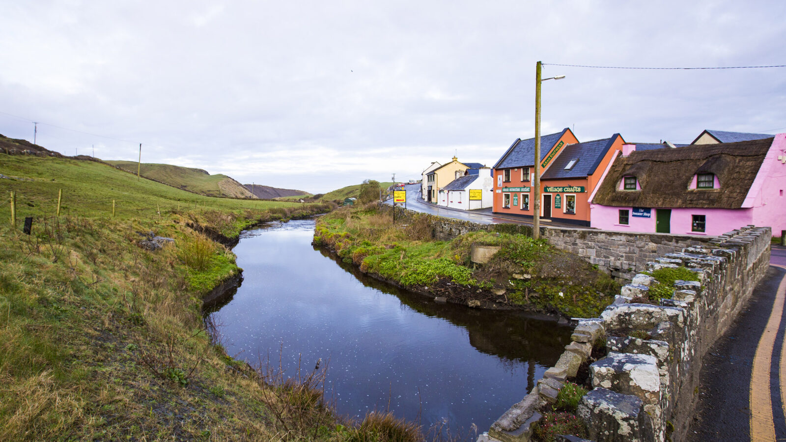 colorful house in Ireland near a stream, field and stone bridge