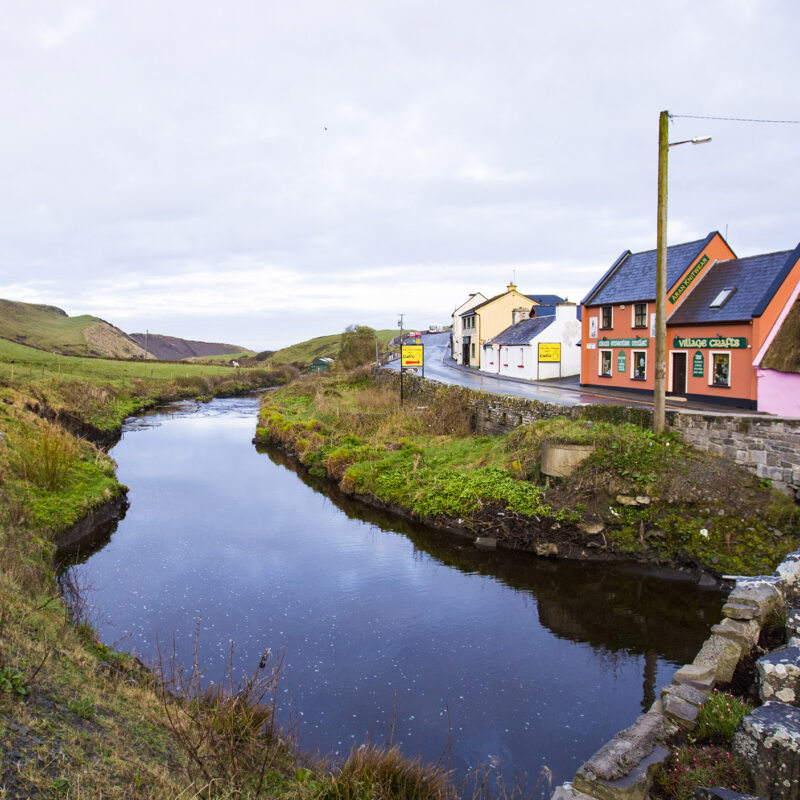 colorful house in Ireland near a stream, field and stone bridge