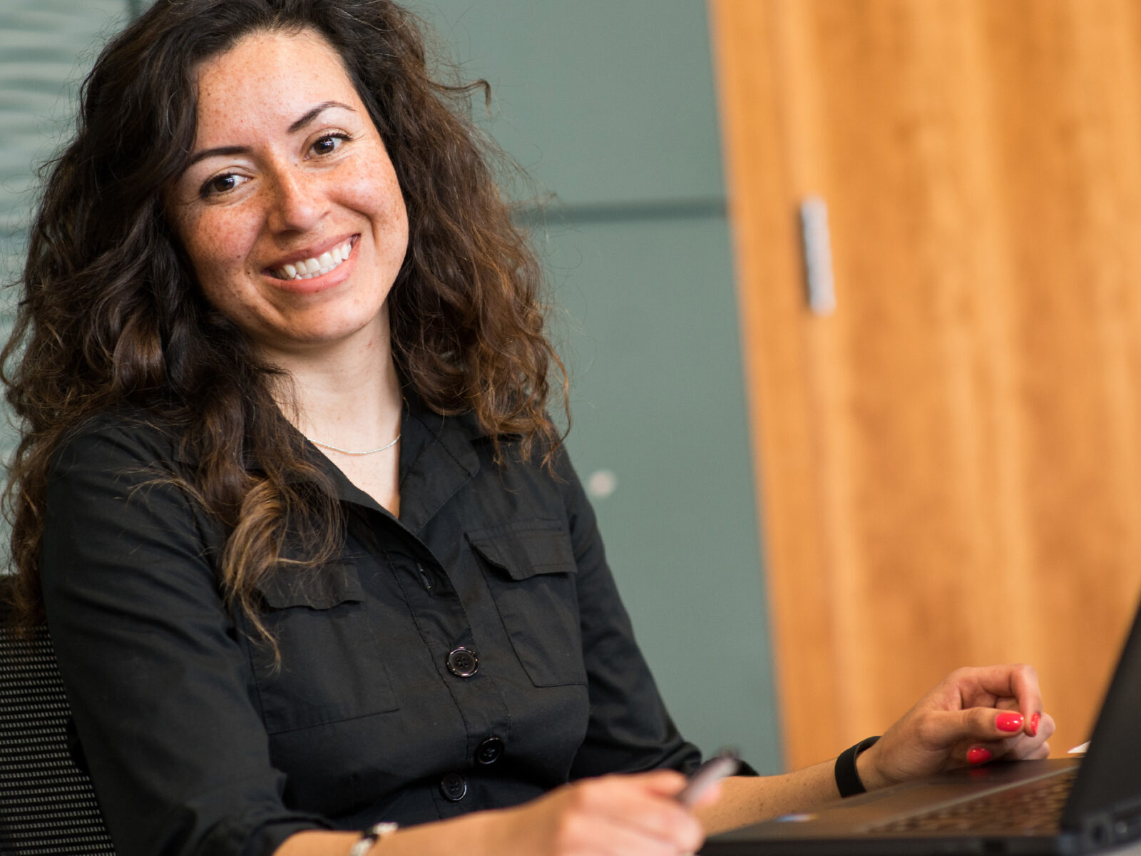 a woman at a laptop smiles at the camera