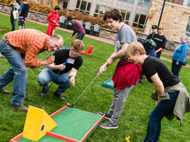 A family plays portable mini golf at Champlain Weekend.